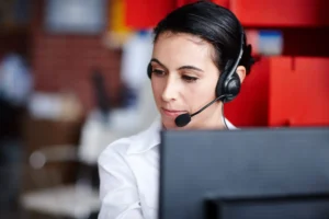 brunette woman working on computer wearing telephone support headset