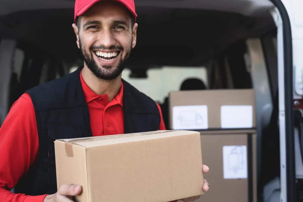 happy delivery driver in red hat and shirt holding a package