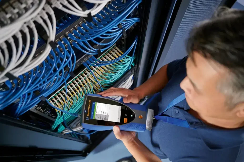 lifestyle shot of technician using a trend networks signaltek 10g pro testing device on a server rack